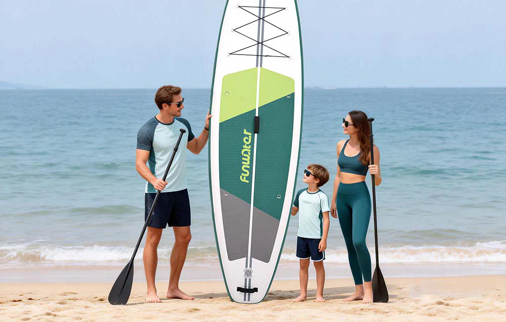 Familie cu un copil pe plajă, bărbat ținând o placă de surf și o vâslă