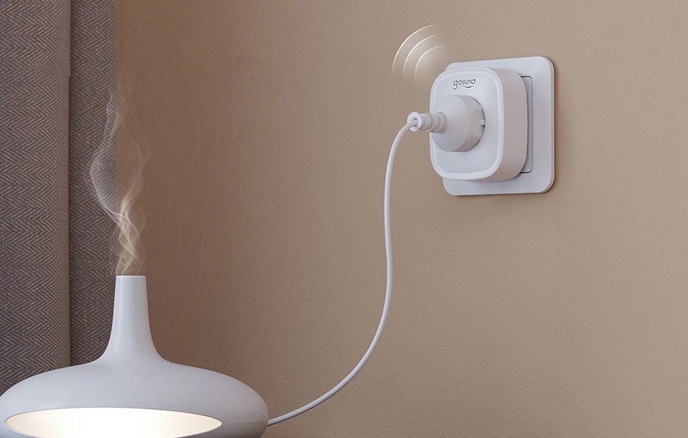 O priză inteligentă Gosund cu un umidificator conectat care emite vapori de apă, montată pe perete lângă o perdea