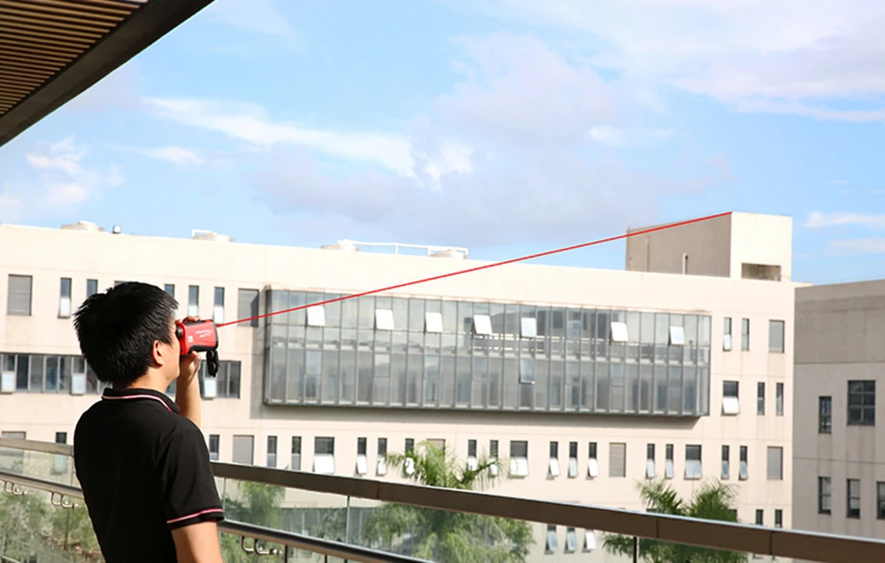 Un bărbat măsoară distanța de la balcon la clădire folosind un telemetru laser Uni-T