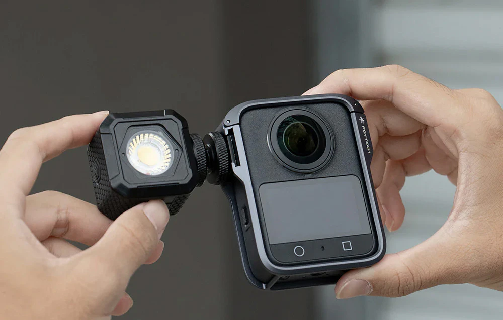 Persoană care ține camera DJI în carcasă și montează o lumină pe aceasta