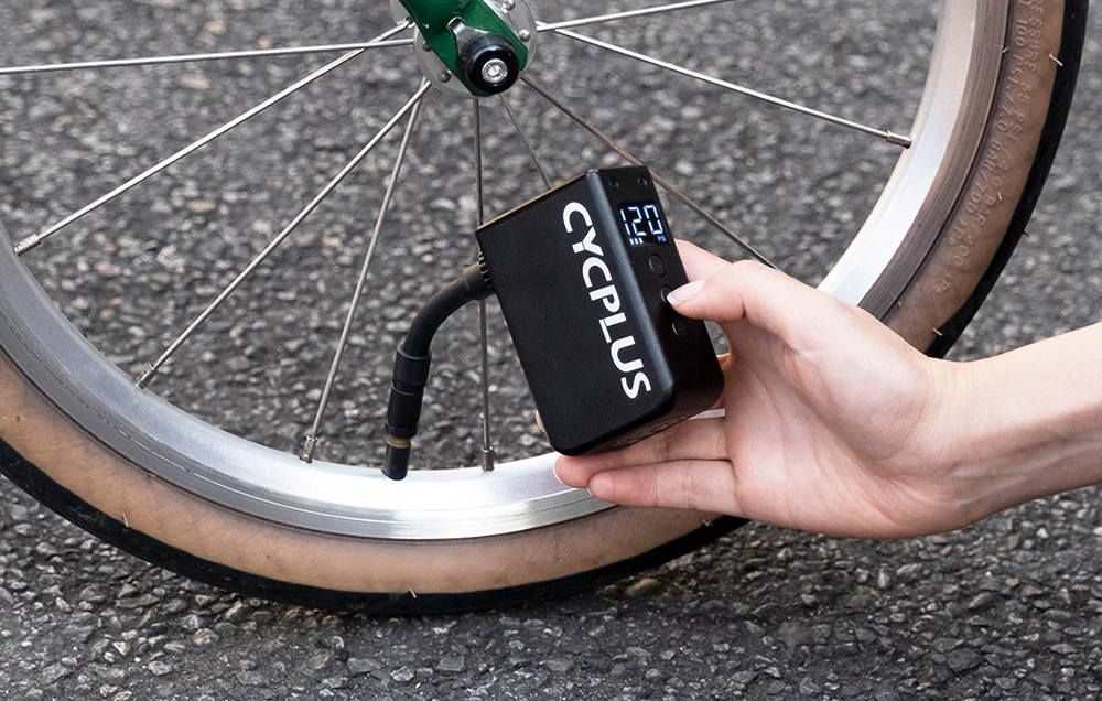 Umflarea unei anvelope de bicicletă cu o pompă electrică neagră