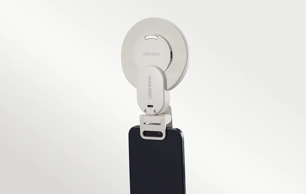 O lampă inelară albă montată pe un smartphone negru, vedere din spate pe un fundal luminos