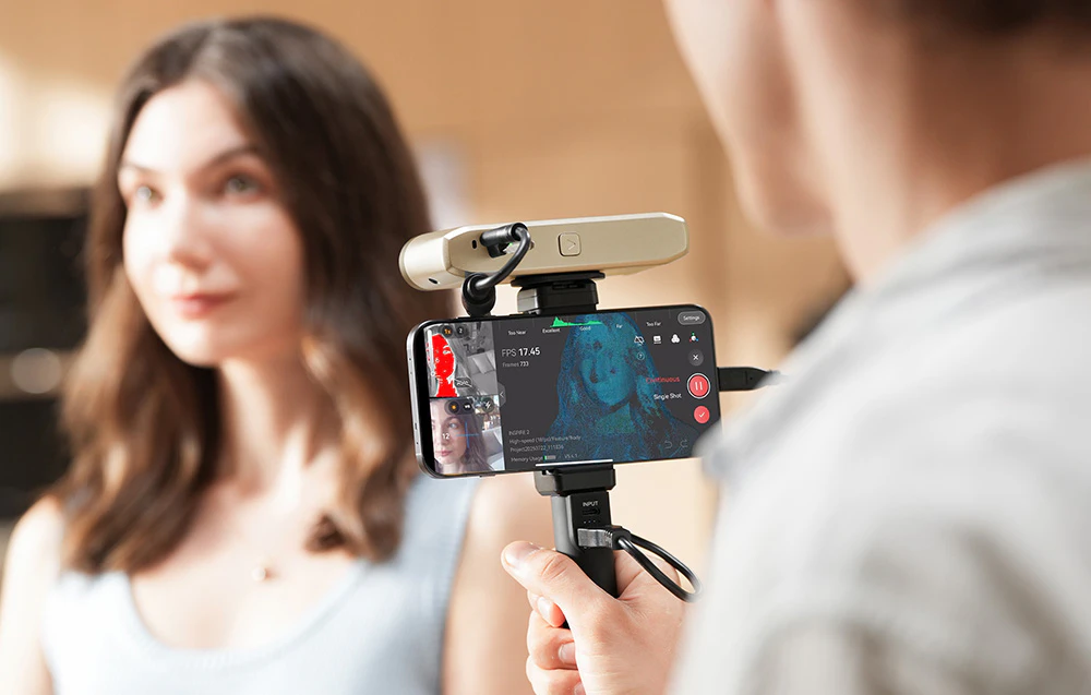 Previzualizare a procesului de scanare 3D a feței unei femei pe ecranul unui smartphone montat sub scaner
