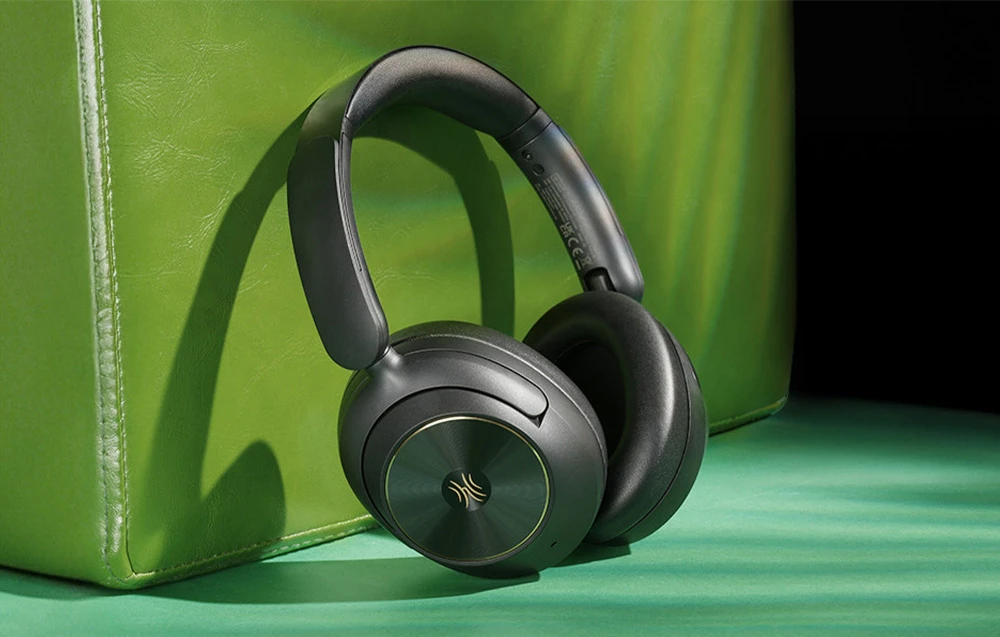 Căști in-ear negre sprijinite pe o suprafață din piele verde