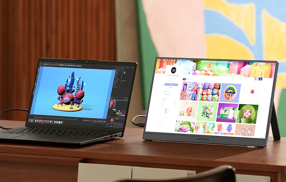 Laptop cu un program de grafică deschis, așezat pe un birou lângă un monitor Arzopa