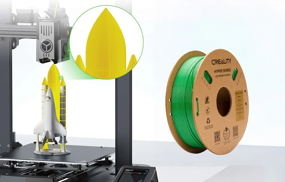O rachetă galbenă și albă imprimată pe o imprimantă 3D lângă o bobină de filament verde