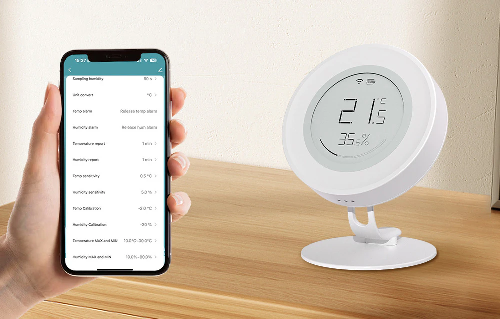Senzor montat pe un blat lângă un smartphone, cu setările parametrilor de temperatură și umiditate în aplicație
