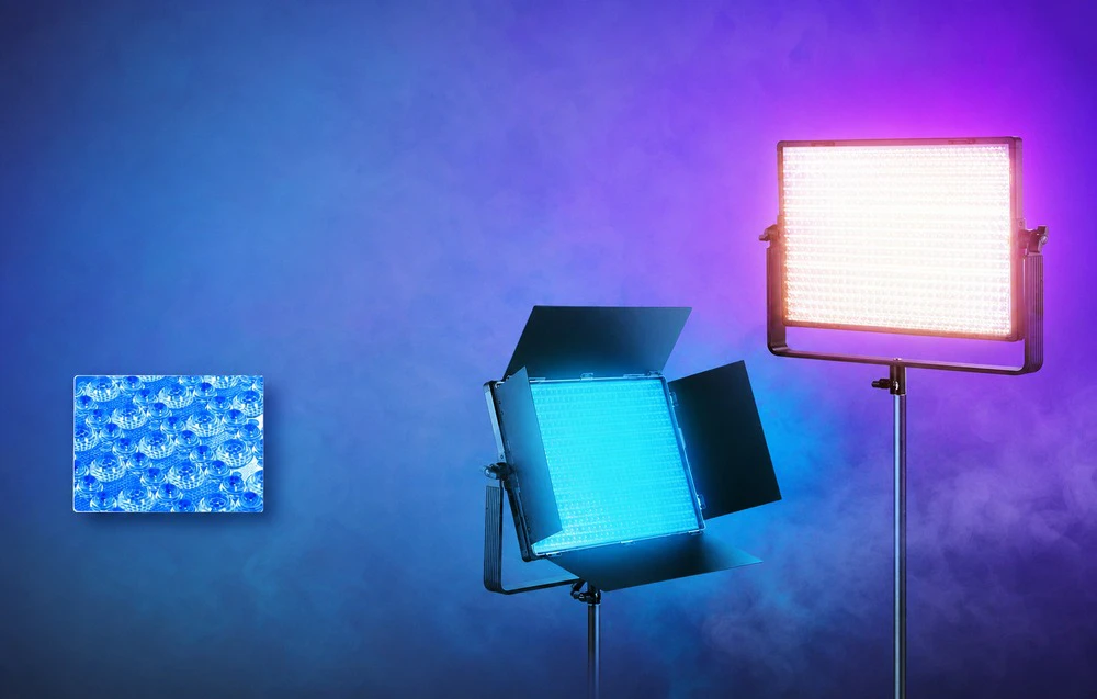 Două lămpi de iluminat dreptunghiulare pe trepiede strălucind cu lumină albastră și violetă intensă.