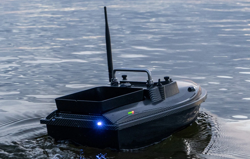 Barca de momeli RC din carbon cu lumini LED albastre și verzi, container de momeală negru la amurg