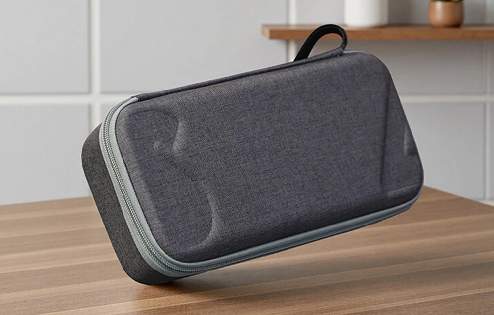Valiză închisă din material textil gri cu fermoar și mâner pe partea superioară din lemn cu interior luminos