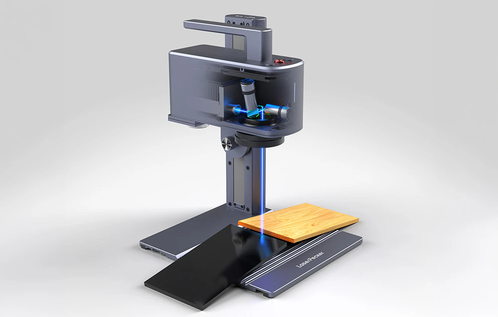 Gravator laser, două materiale pe masa de lucru, obiecte pe fond gri