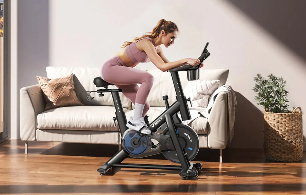 O femeie face exerciții intense pe o bicicletă staționară în sufragerie