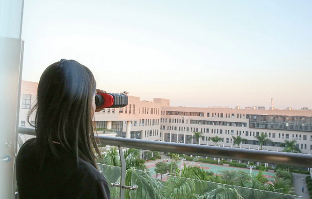 O femeie folosește un telemetru laser Uni-T pe un balcon.