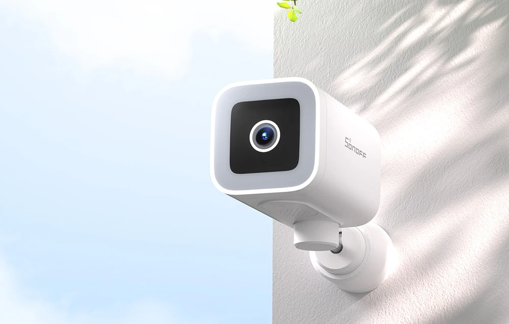 Cameră de securitate SONOFF albă montată pe colțul unui perete exterior alb