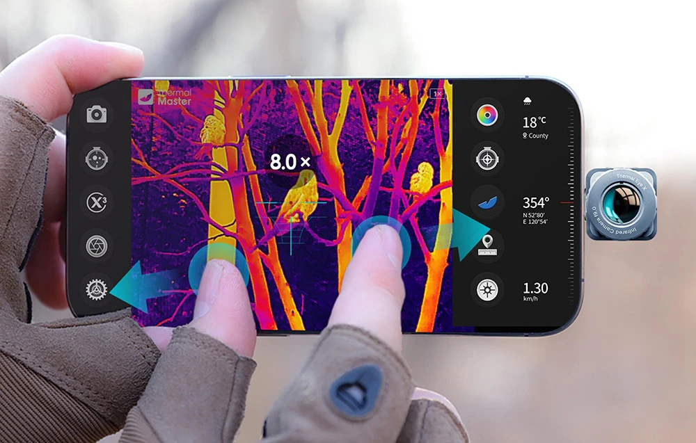 Mâinile înmănușate operează un smartphone care afișează o imagine termică a păsărilor din copaci și o mică cameră atașată.