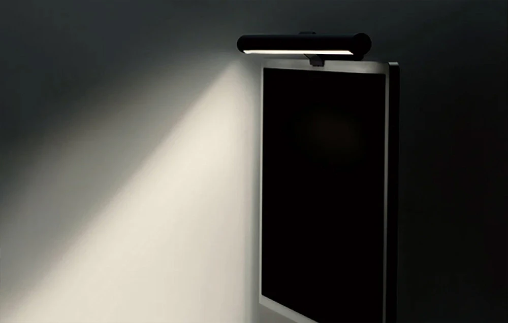 Lampa neagră Yeelight pentru monitor emite un fascicul puternic de lumină pe un fundal întunecat, iluminând zona înconjurătoare