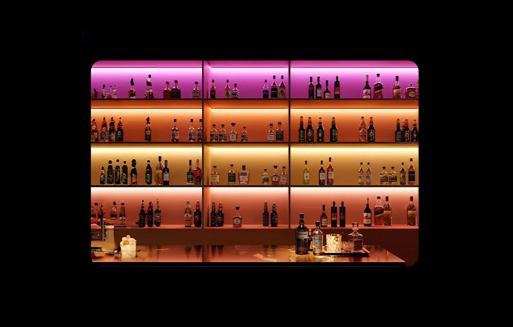 Raft pentru băuturi de bar iluminat cu benzi LED colorate în nuanțe de violet, portocaliu și auriu
