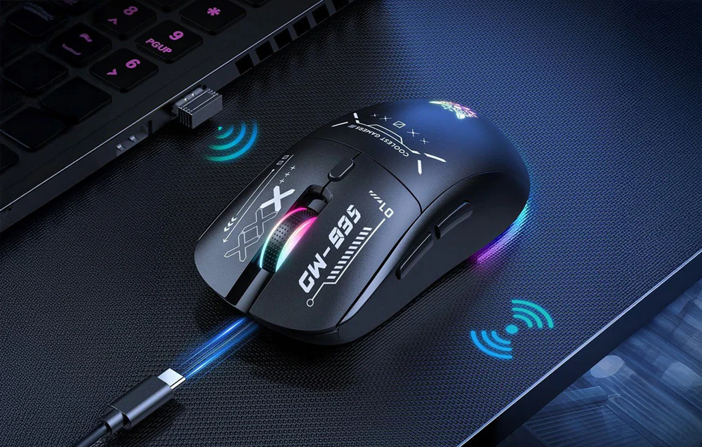 Mouse negru pe o masă întunecată lângă un laptop cu receptor și cablu USB-C
