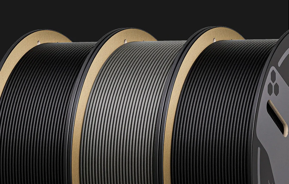 Un prim-plan cu trei bobine de filament negru pentru imprimante 3D aliniate una lângă alta