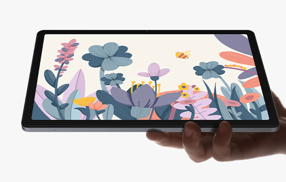 Mână care ține o tabletă cu ilustrații pastelate de flori, fluturi și plante pe fundal alb