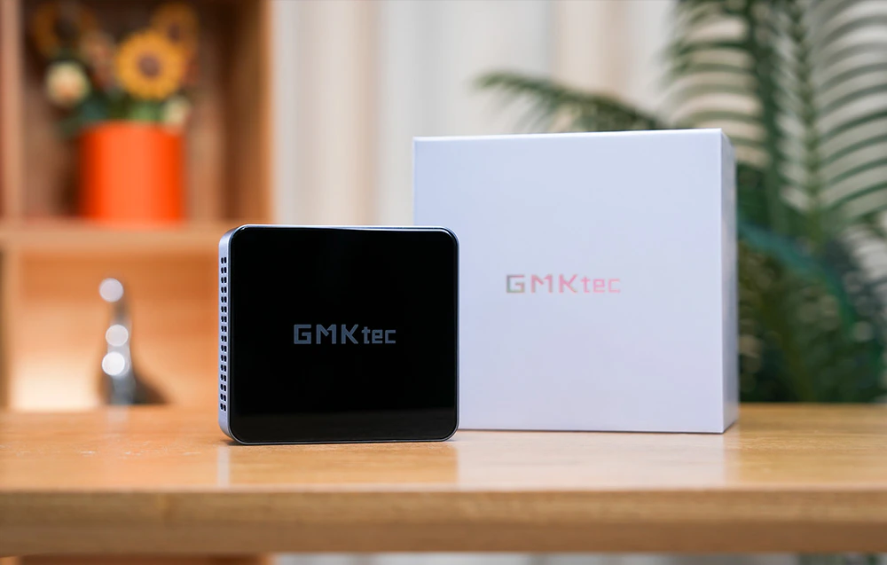 Mini PC-ul GMKtec M3 Pro așezat lângă ambalajul original pe o masă din lemn.