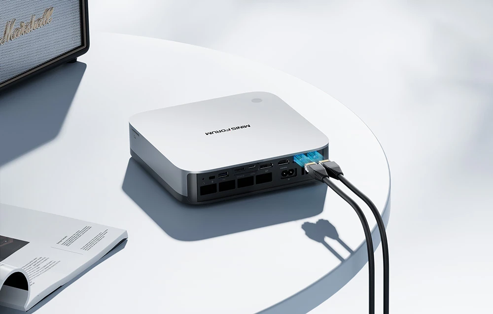 Panoul din spate al unui Mini PC alb cu cabluri de rețea conectate și porturi USB și HDMI vizibile.