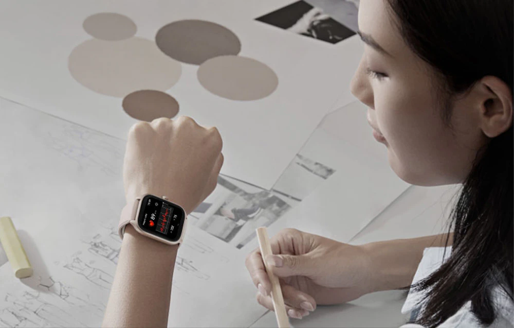 O femeie care lucrează la birou se uită la smartwatch-ul de pe încheietura mâinii sale