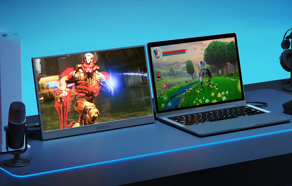 Monitor Arzopa lângă un laptop și un microfon pe un birou gri