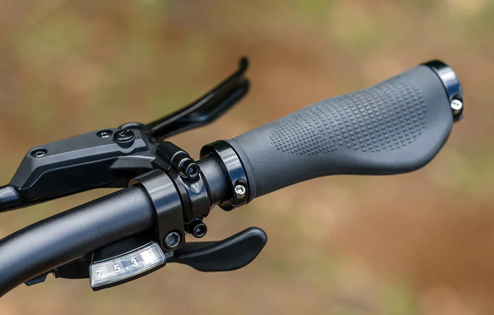 Prim-plan al ghidonului bicicletei electrice cu mâner ergonomic, schimbător de viteze și manetă de frână