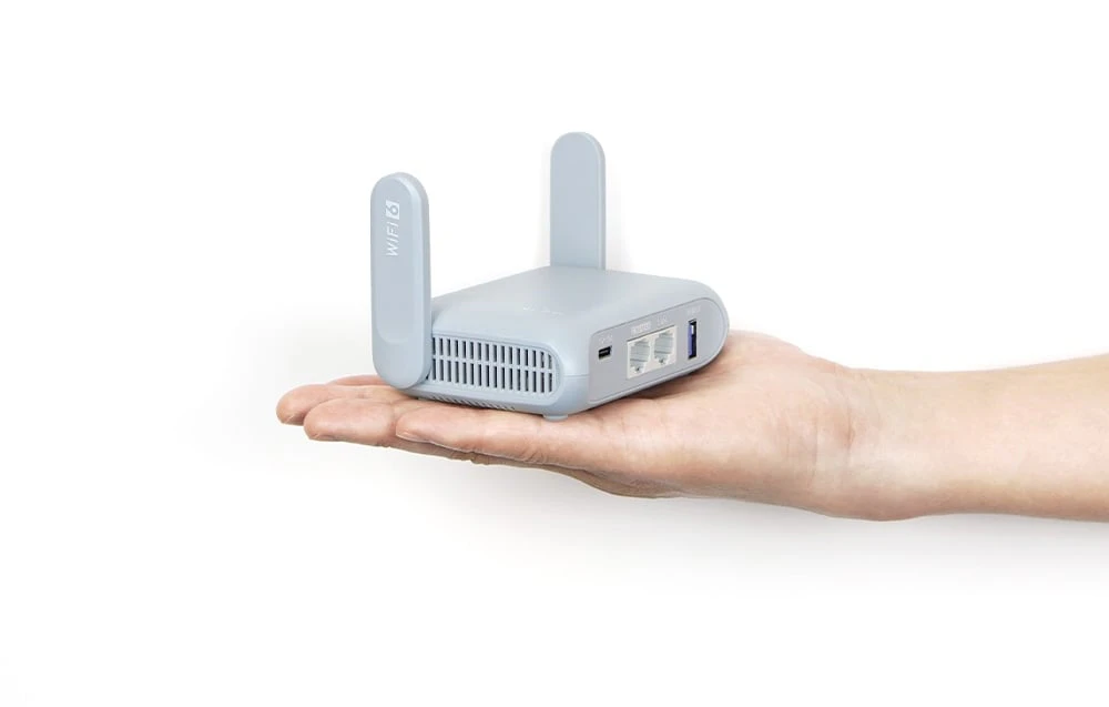 Un router gri cu antene ținut într-o mână pe un fundal deschis