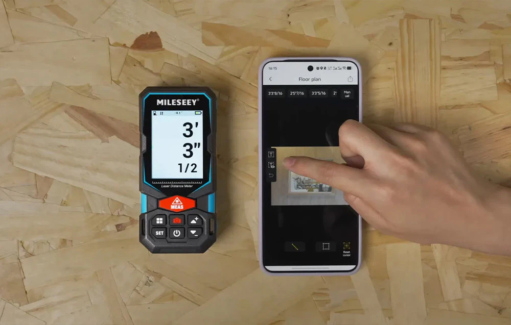 Un telemetru laser lângă un smartphone cu o aplicație pentru crearea planurilor de etaj.