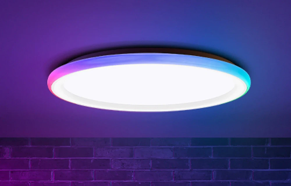 Plafonieră Yeelight Mars C400 care emite lumină albă și colorată pe un perete de cărămidă.