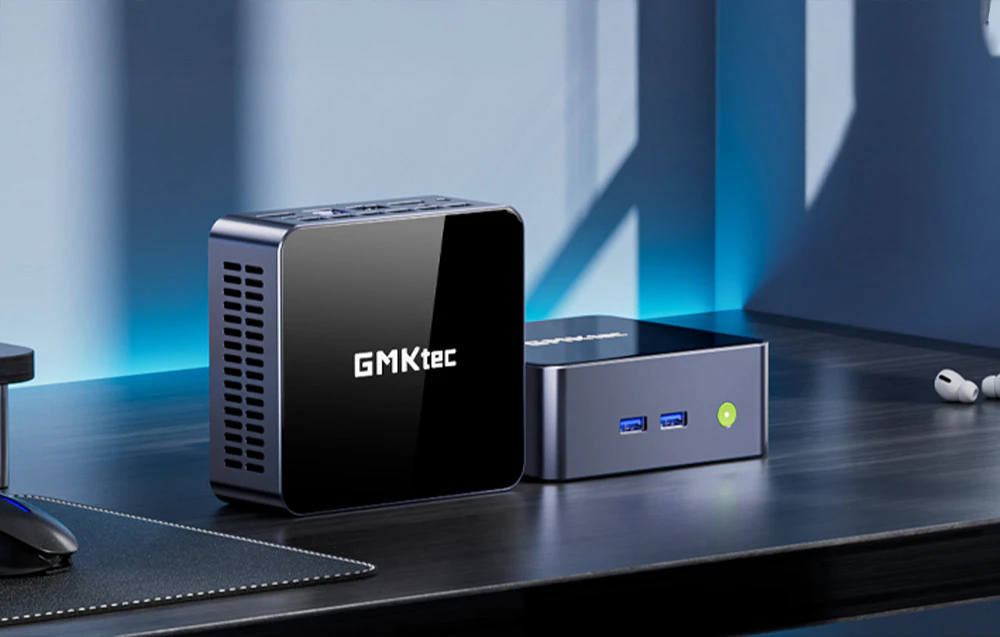 Două PC-uri GMKtec pe un birou - unul pe verticală, celălalt pe orizontală, cu accesorii în fundal