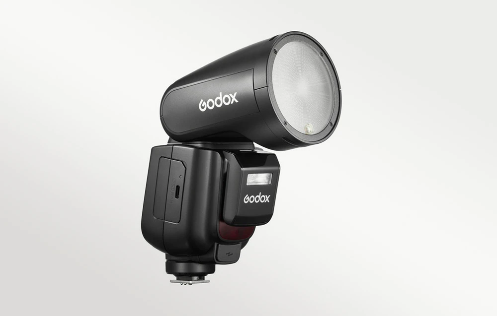 Unitatea de bliț Godox V1Pro neagră, văzută din profil, cu un bliț auxiliar atașat