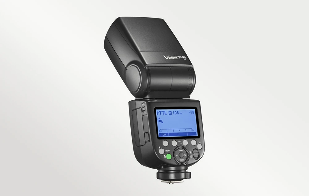Blițul Godox V860III cu capul înclinat, ecranul LCD aprins și butonul de testare verde