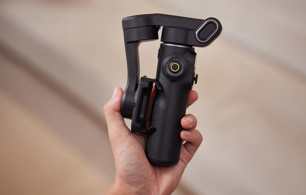 O mână care ține un gimbal pliat într-o formă compactă.