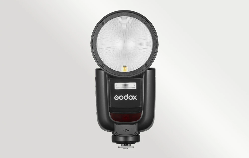 Blițul Godox V1Pro C văzut din față, prezentând capul rotund de bliț și logo-ul mărcii