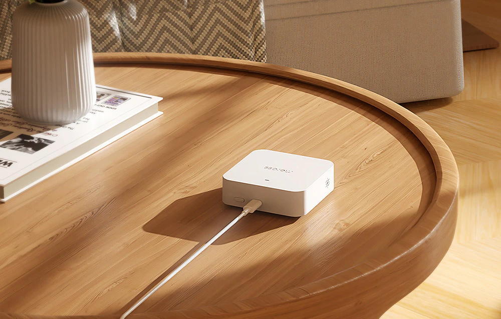 Gateway Wi-Fi inteligent MEROSS conectat la un cablu, așezat pe o masă din lemn