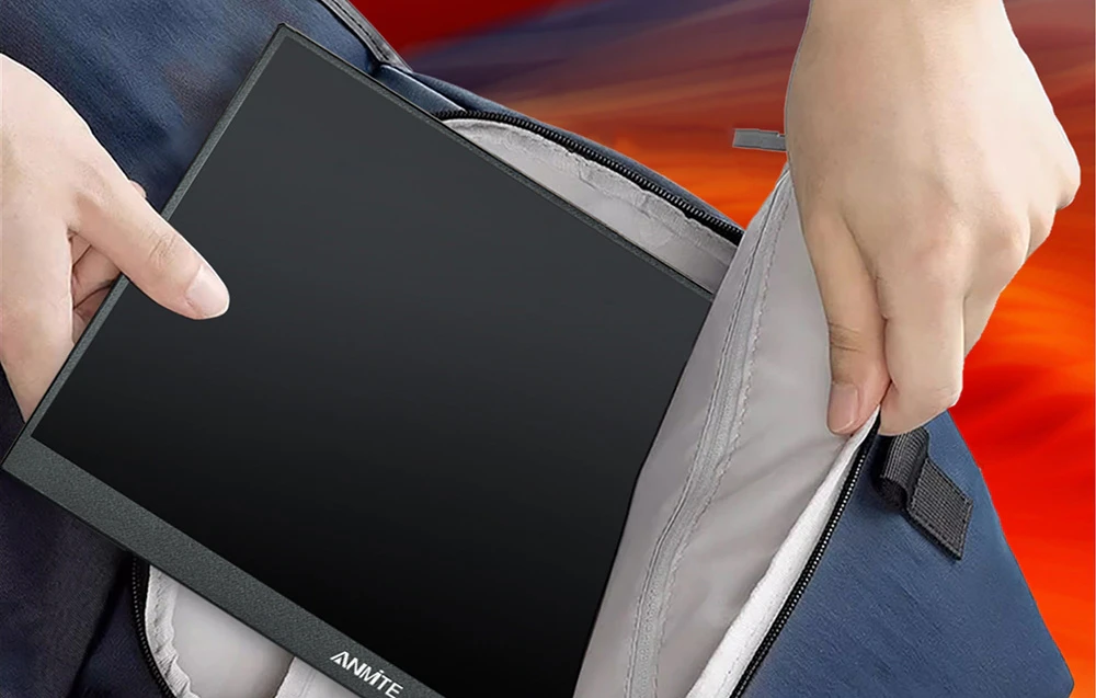 Mâini care introduc un monitor negru, plat, într-o geantă de călătorie albastră.