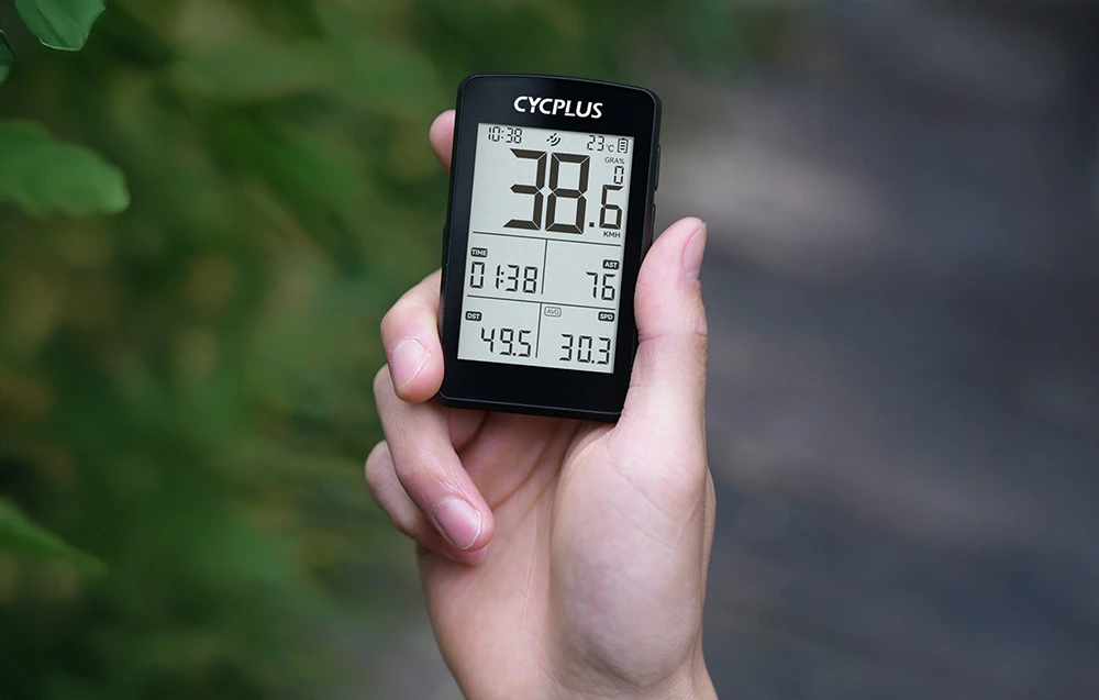Mână care ține calculatorul Cycplus M3 cu ecran pe fundal de frunze verzi