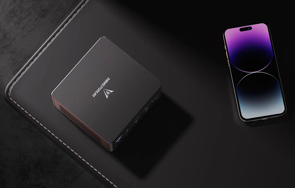 mini PC negru pe un covor negru, lângă un smartphone