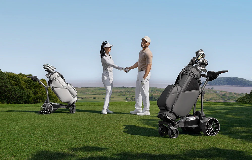 Jucătorii de golf își strâng mâinile pe terenul de golf, cu două cărucioare de golf automate de o parte și de alta