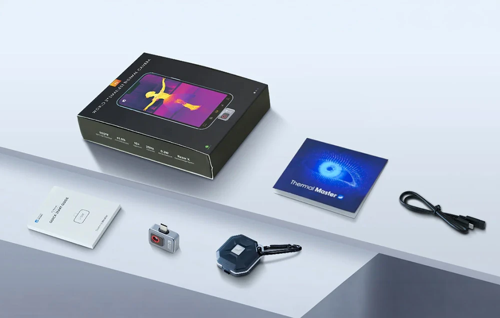 Pe masă se află o cutie cu eticheta WORLD'S SMALLEST THERMAL CAMERA (Cea mai mică cameră termică din lume), manualul Thermal Master, un cablu, accesorii și o mini cameră termică