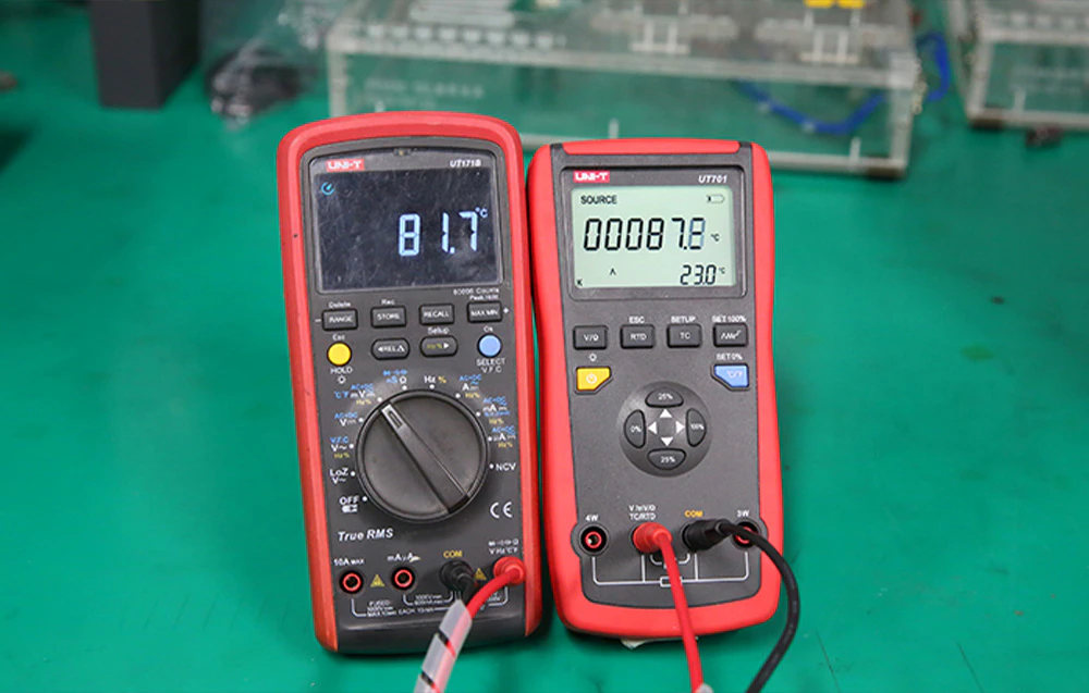 Multimetru digital și calibrator de temperatură conectate prin cabluri în timpul testării semnalului de la senzorul de temperatură.