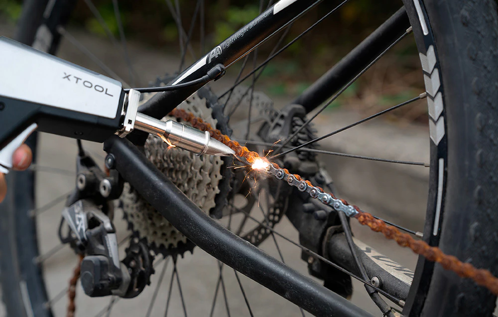 un sudor cu laser lucrează la un lanț de bicicletă