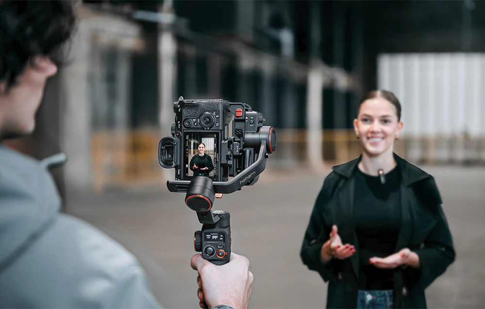 Un băiat ținând o cameră pe un gimbal și filmând o fată