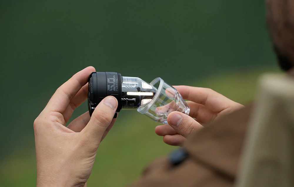 Un bărbat îndepărtează capacul transparent de pe pompa neagră, dezvăluind lampa de camping integrată