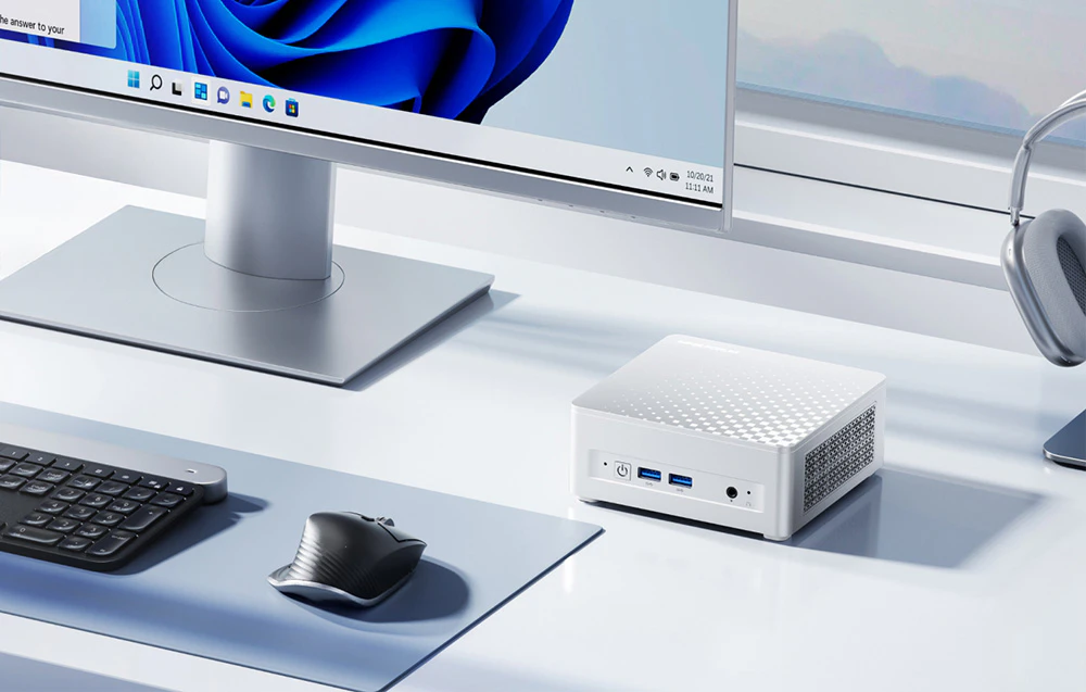 mini PC alb, monitor, mouse, tastatură, căști pe un birou