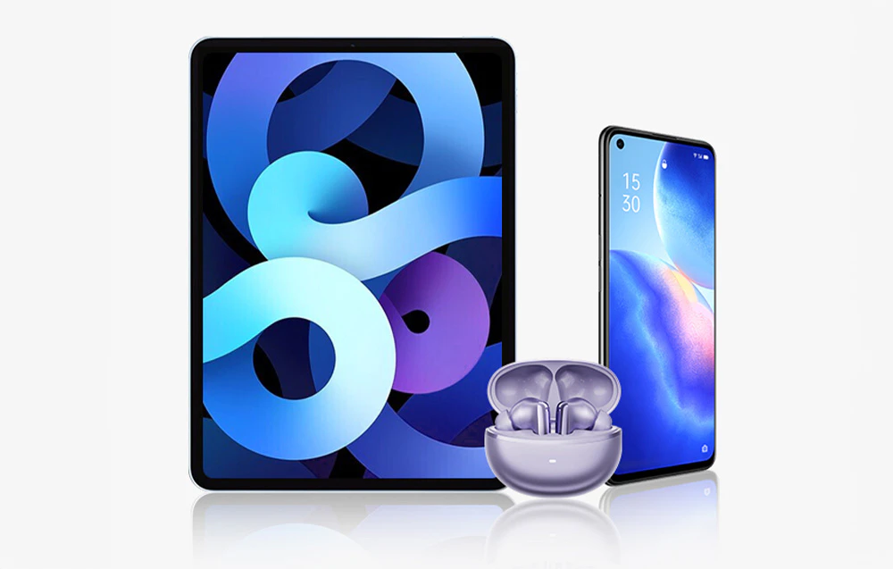 Căști fără fir violet într-o carcasă așezată în fața unei tablete și a unui smartphone