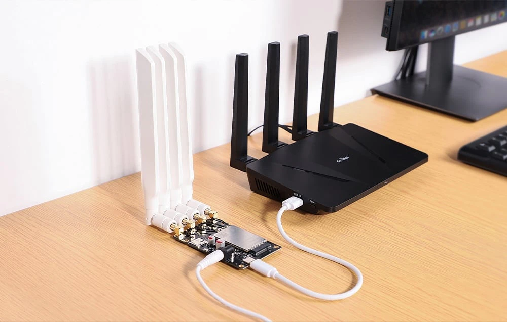 Un router negru conectat printr-un cablu USB alb la o placă de circuit verde așezată lângă el, prevăzut cu patru antene albe